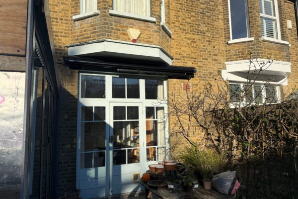 Closed Markilux awning above French doors in a narrow rear courtyard in Herne Hill