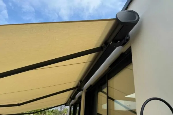 Close-up underneath patio awning showing fabric, arms and housing