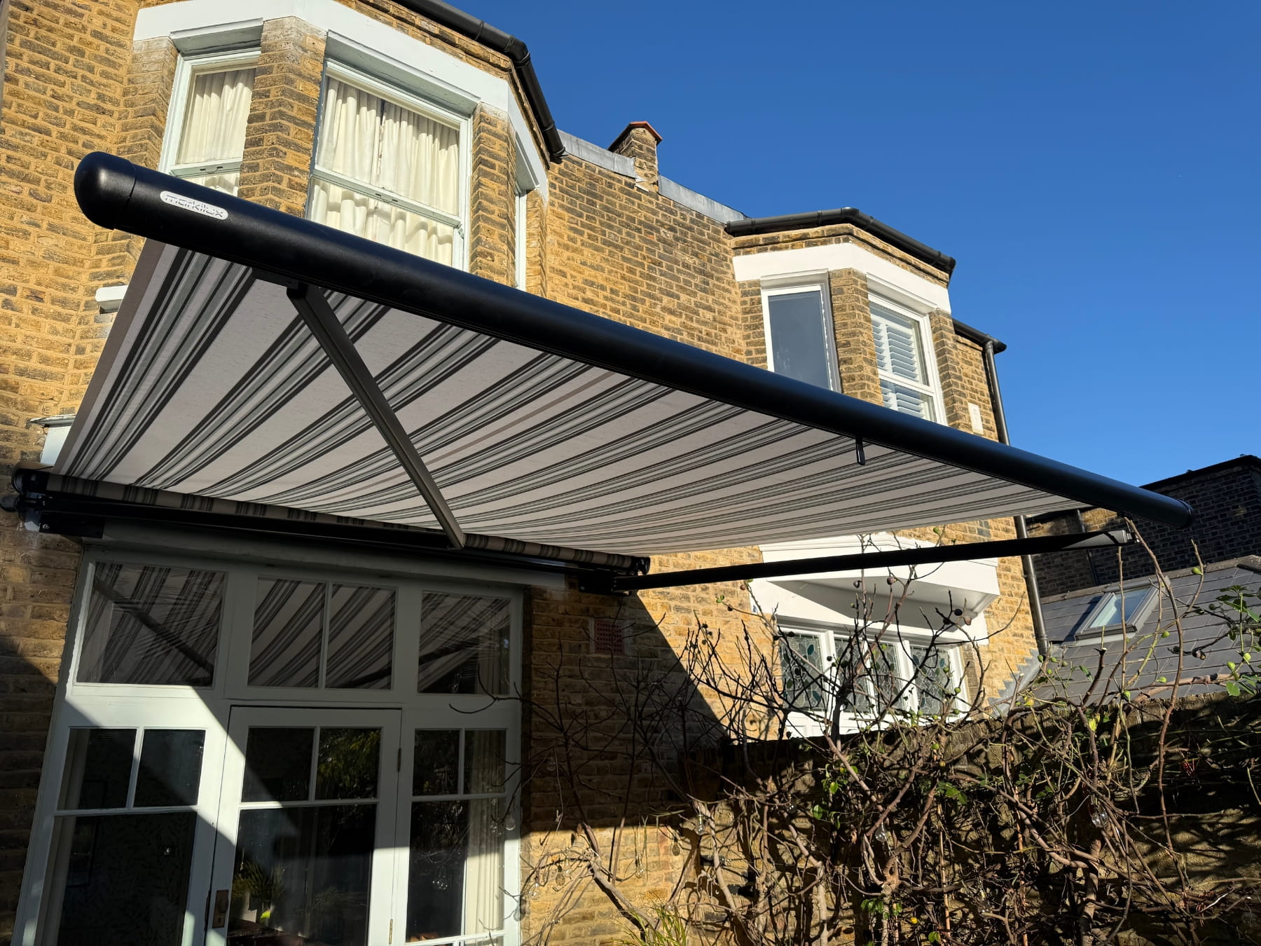 lose-up of striped Markilux awning fabric and arms from below